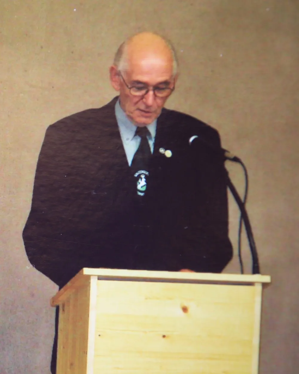 Willi Weisser am Rednerpult, im Anzug mit Vereinsabzeichen am Revers.
